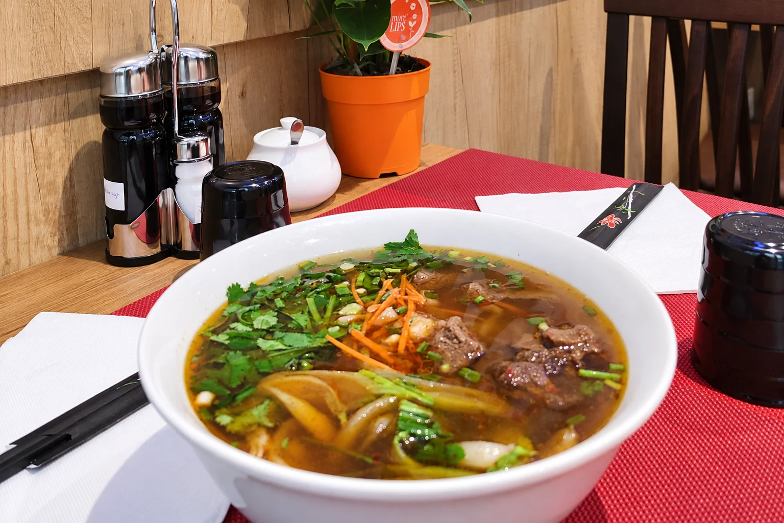 Soupe de nouilles dans un bol blanc, set de table rouge
