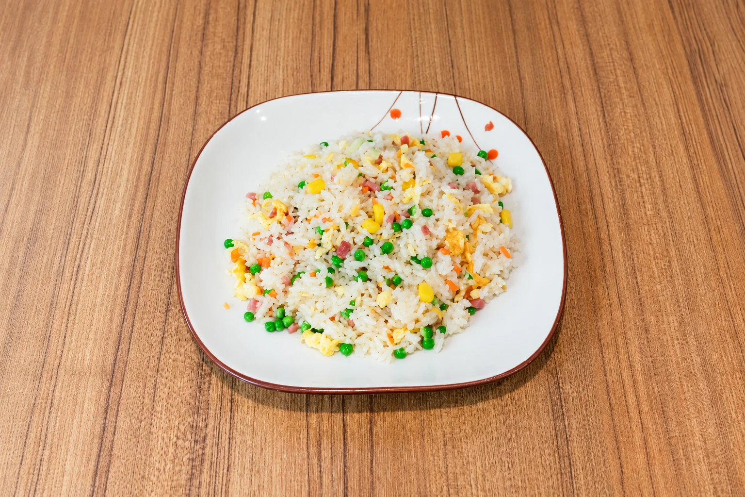 Riz cantonnais dans une assiette à liseré brun, table en bois